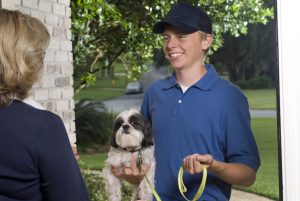 Smiling dog walker dropping off a dog to its female owner